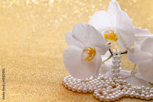 Fototapeta Naklejka Na Ścianę i Meble -  White Orchid and pearl necklace on a shiny gold background
