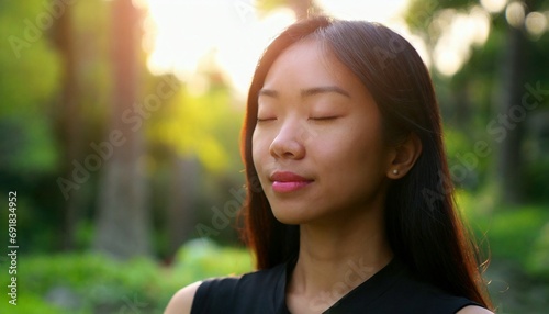 Young Asian woman in serene meditation, surrounded by nature's glow