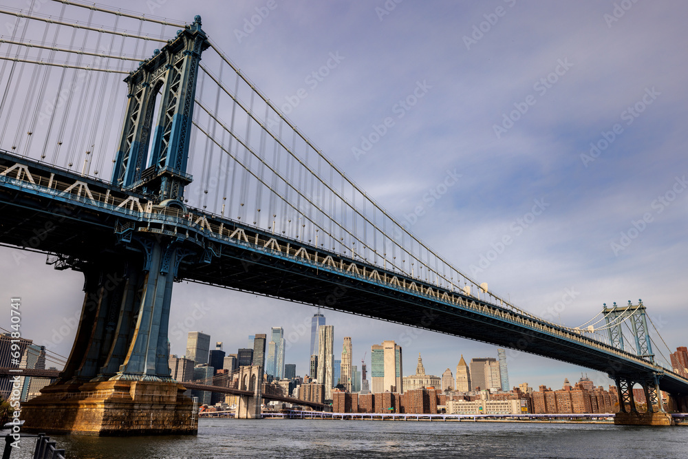 The Manhattan Bridge crosses the East River in New York City, with the skyline of downtown Manhattan in the background