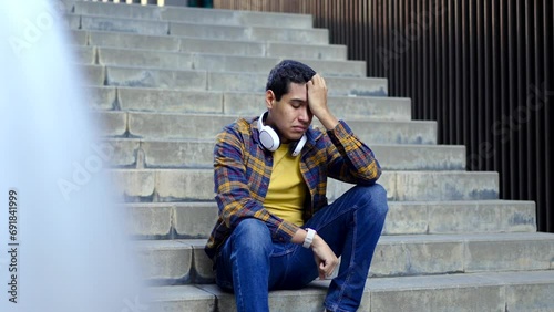 Horizontal video with slow motion of a worried hispanic young student sitting in an outdoor stairs thinking with hand on head