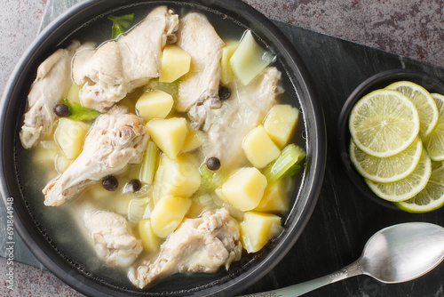 Bahamian stew with chicken wings, potatoes, celery, lime and spices in a clear broth close-up in a plate on the table. Horizontal top view from above