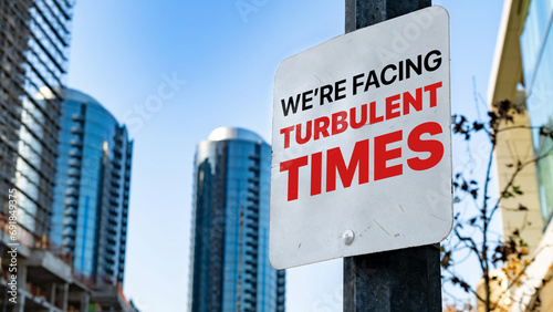 Fotografija We're facing turbulent times on a sign in a city business district