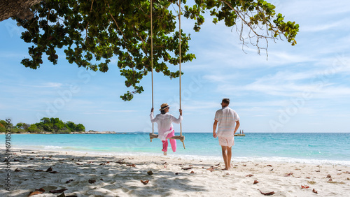 Canvas Print A couple of men and women at a swing on the beach of Koh Samet Island Rayong Thailand, the white tropical beach of Samed Island with a turqouse colored ocean