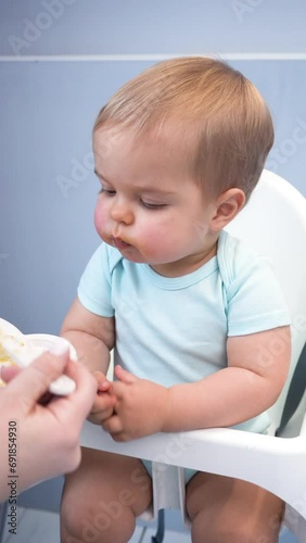Mother feeds her baby son with vegetable puree. Healthy food. Vertical video.