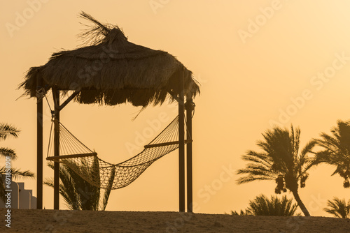 cozy place with a hammock and palm trees during sunset