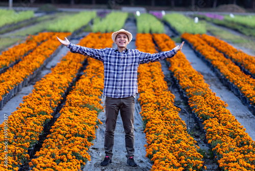 Asian gardener is welcoming people into his cut flower farm full of orange marigold for medicinal and garnish in the fine dining restaurant business