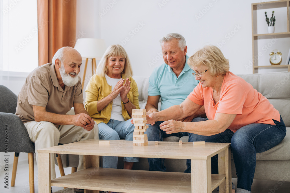 Group of happy senior people having fun and playing board games in retirement home