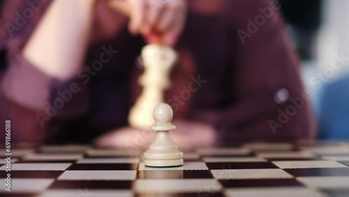 A focused chess player contemplates a move, pawn at the ready. The strategic decision echoes life's complex choices. pawn stands alone on the chessboard; a decisive moment. photo