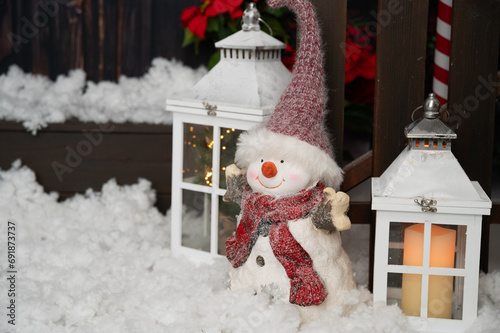 Christmas and new year background. Christmas decoration with a cute cheerful snowman and lanterns in the snow in front of a house photo