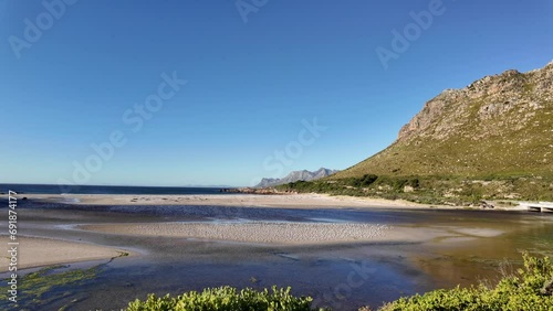 View of the gorgeous Rooi Els beach and estuary with the Kogelberg Mountains and Clarence Drive in the background an a common tern (Sterna hirundo) colony on the sandbank. Western Cape. South Africa. photo
