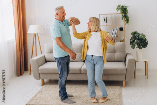 Happy senior couple dancing to music together in living room