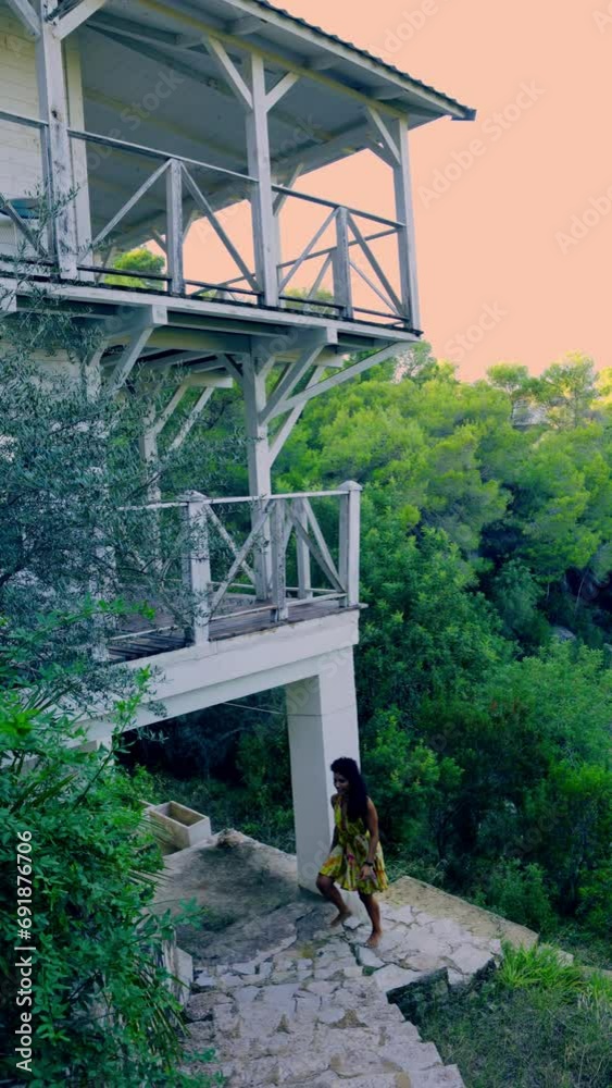 Barefoot woman in dress climbing the stairs of a colonial hotel in the middle of nature Barefoot woman in dress climbing the stairs of a colonial hotel in the middle of nature