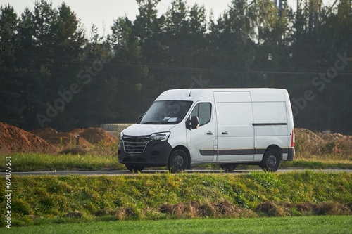 White van. Delivering to Suburban Homes. Commercial Van on the Road Cargo Delivery in the Countryside. Light-Duty Truck in Action.