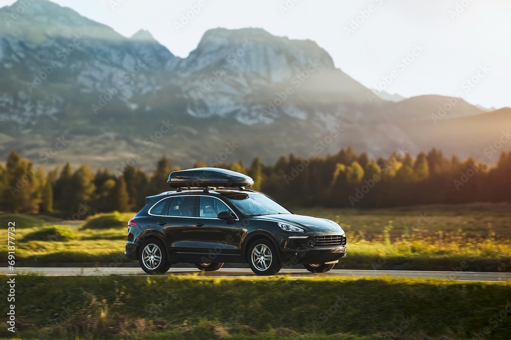 Expensive family SUV with Luggage box mounted on the roof. Extra Capacity for the Road. Black SUV with Roof Rack.