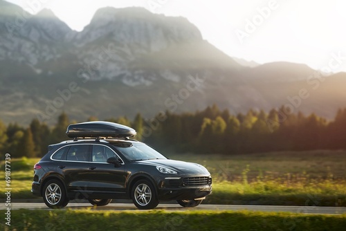 Expensive family SUV with Luggage box mounted on the roof. Extra Capacity for the Road. Black SUV with Roof Rack.