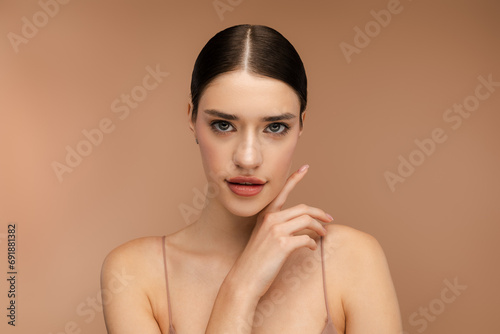 Young woman with natural makeup posing and looking at camera Isolated on beige background. Skin care, beauty procedure, morning routine concept