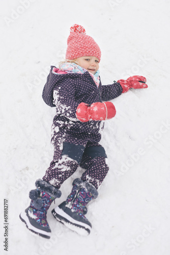 Two years old girl enjoying snow and ice in frozen city park