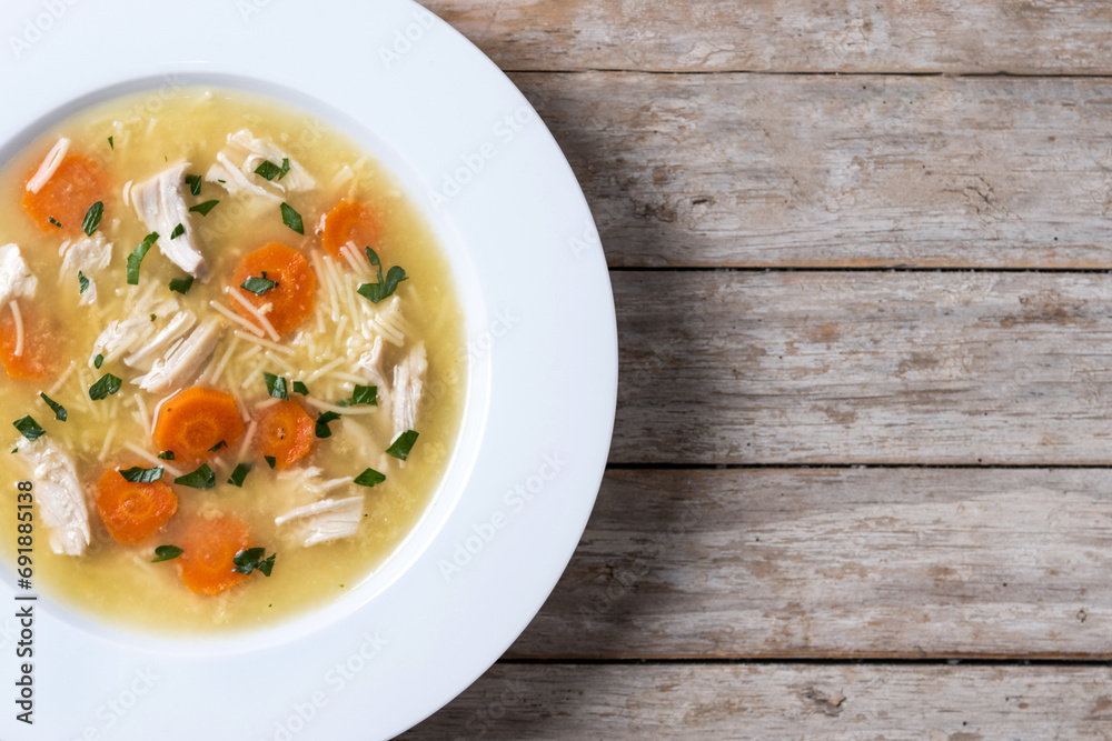 Chicken soup with vegetables on wooden table. Top view. Copy space Chicken soup with vegetables on wooden table. Top view. Copy space