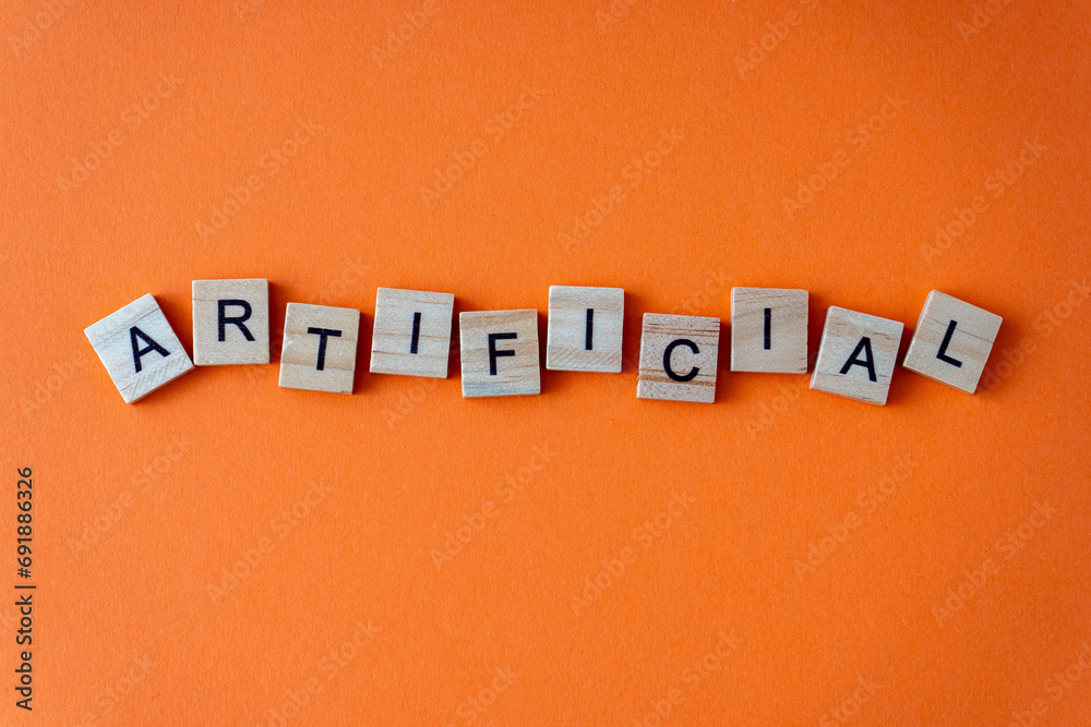 Obraz premium Word artificial. The phrase is laid out in wooden letters top view. Orange flat lay background