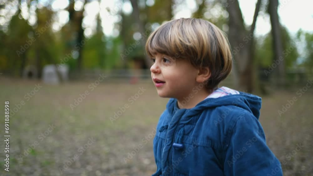 Child Walking in Outdoor Park, Autumn Season with Jacket. One caucasian blond child exploring nature walking forward Child Walking in Outdoor Park, Autumn Season with Jacket. One caucasian blond child exploring nature walking forward