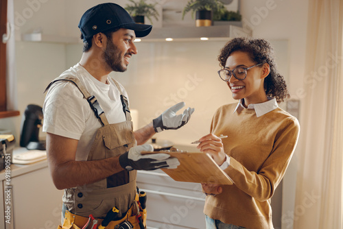 Smilng young woman signing document while communicating with handyman at the kitchen photo