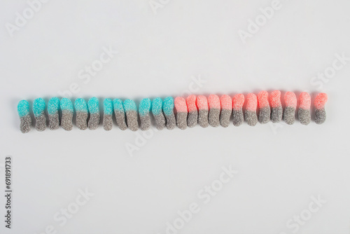 Sour tasting colorful gummy worms as line on white background