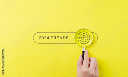 Trends 2024 year concept. Hand holding magnifying glass with 2024 trend searching bar for optimization 2024 business marketing trends and business plan in new year. Find information and new ideas. photo