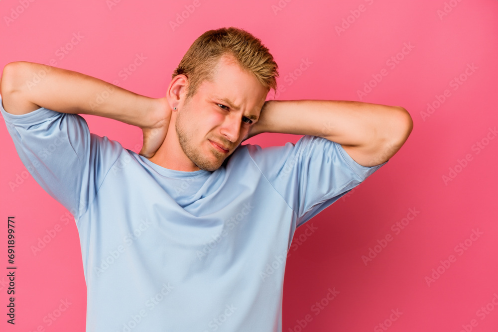 man's neck pain. a man in a T-shirt stands on a pink background holding his sore neck, the man makes a face in pain man's neck pain. a man in a T-shirt stands on a pink background holding his sore neck, the man makes a face in pain