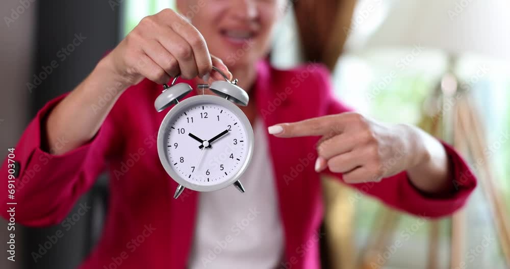 Businesswoman points to alarm clock for ten o'clock at workplace. Planning work agenda time management and overtime work and deadline Businesswoman points to alarm clock for ten o'clock at workplace. Planning work agenda time management and overtime work and deadline
