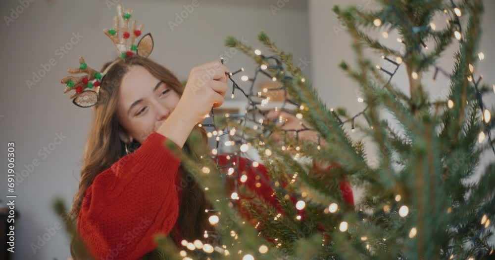 Woman adjusting led lights on Christmas tree Woman adjusting led lights on Christmas tree