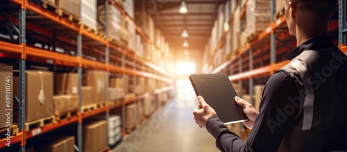 A black warehouse worker checking the delivery status of the package with a tablet in a large distribution center. Copy space image. Place for adding text photo