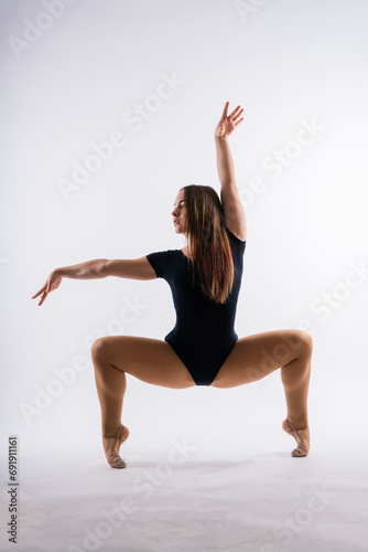 Beautiful plump brown-haired woman in black bodysuit in a studio. Caucasian dancehall dancer posing