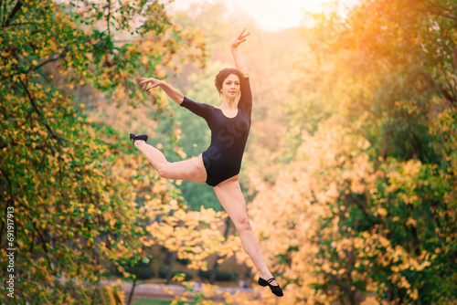 Beautiful female  ballerina  athlete in black bodysuit training in the park