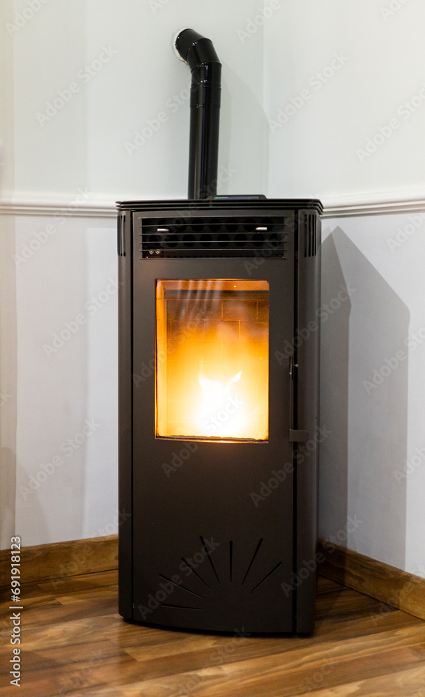 Vertical photo of a pellet stove inside a living room of a house. Renewable energy source.biomass in pellet form. Vertical photo of a pellet stove inside a living room of a house. Renewable energy source.biomass in pellet form.