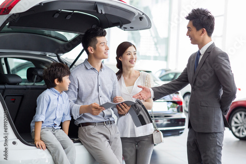 Young family choosing car in showroom photo