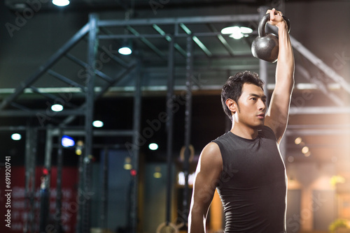 Young man training with kettlebell in crossfit gym photo