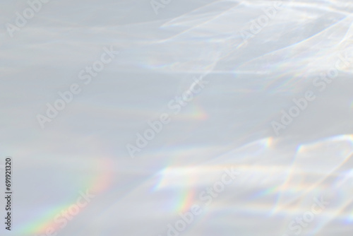  Crystal prism rainbow light refraction texture on white wall background. Organic drop diagonal holographic flare on a white wall. Water shadows for natural light overlay effects