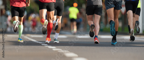 Marathon runners running on city road, large group of runners, close-up legs runners running sport marathon, male jogging race in asphalt road, athletics competition