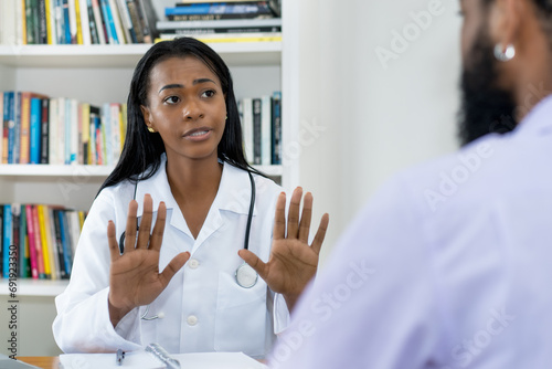 Serious young latin american female doctor warning patient