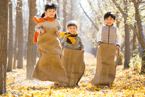 Three children having a sack race in autumn woods photo