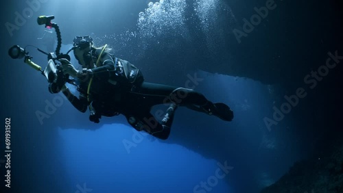 A female SCUBA Diver swims towards camera in an underwater cavern