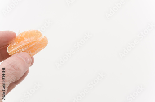 immagine con primo piano di mano che regge frutti di mandarino, clementina su superficie bianca photo