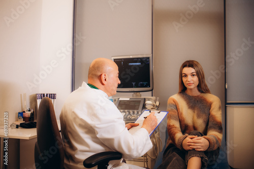 Doctor (obstetrician, gynecologist or psychiatrist) consulting and diagnostic examining woman patient's obstetric - gynecological health in medical clinic or hospital healthcare service center photo