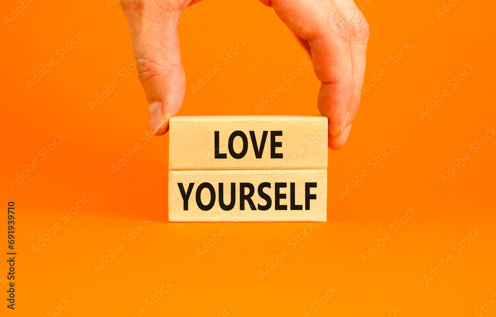 Love yourself symbol. Concept words Love yourself on beautiful wooden blocks. Beautiful orange table orange background. Businessman hand. Psychology love yourself concept. Copy space. - obrazy, fototapety, plakaty 