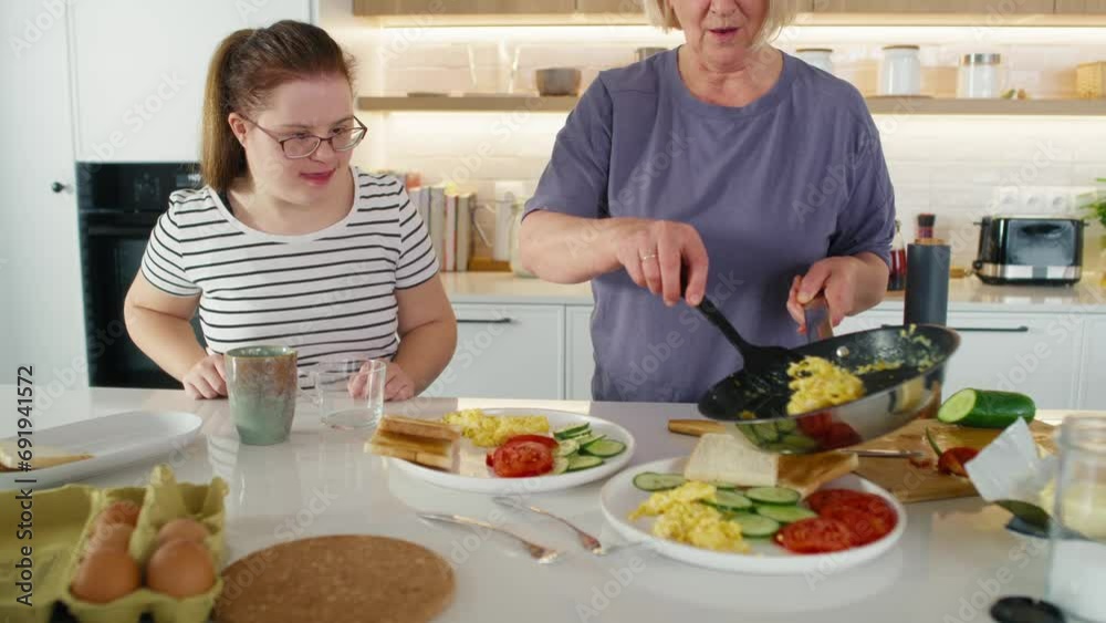 Down syndrome woman and her mother serving breakfast together. Shot with RED helium camera in 8K. Down syndrome woman and her mother serving breakfast together. Shot with RED helium camera in 8K.