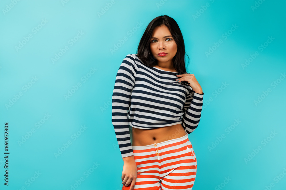girl in a suit. a tanned slender girl with black long hair in a striped suit stands on a blue background girl in a suit. a tanned slender girl with black long hair in a striped suit stands on a blue background