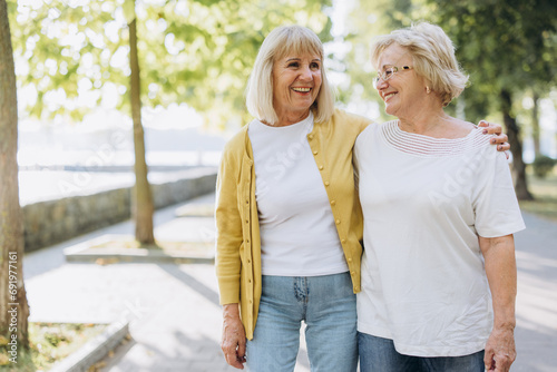 Two happy senior women blonde hairs or friends walking in the park