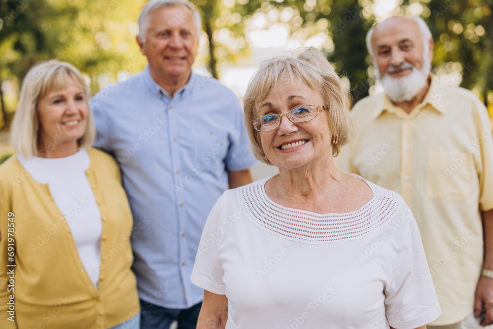 Senior blonde woman against the background of group of old people in park Senior blonde woman against the background of group of old people in park