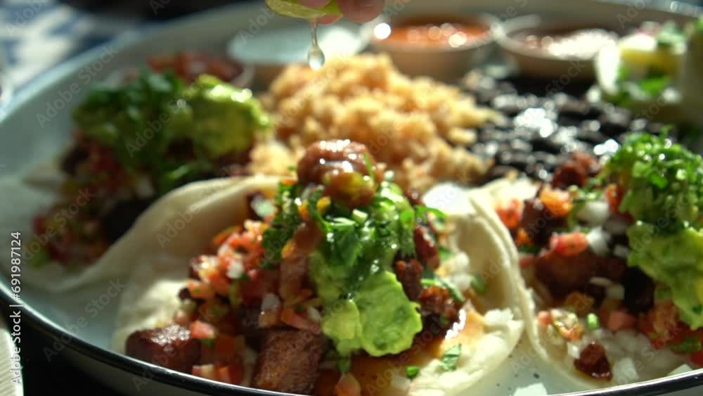Hand sqeezing lime lemon over soft carnitas avocado taco Mexican salsa food Hand sqeezing lime lemon over soft carnitas avocado taco Mexican salsa food