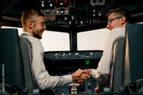 pilots in the cockpit of the plane greet each other and shake hands before the start of the flight